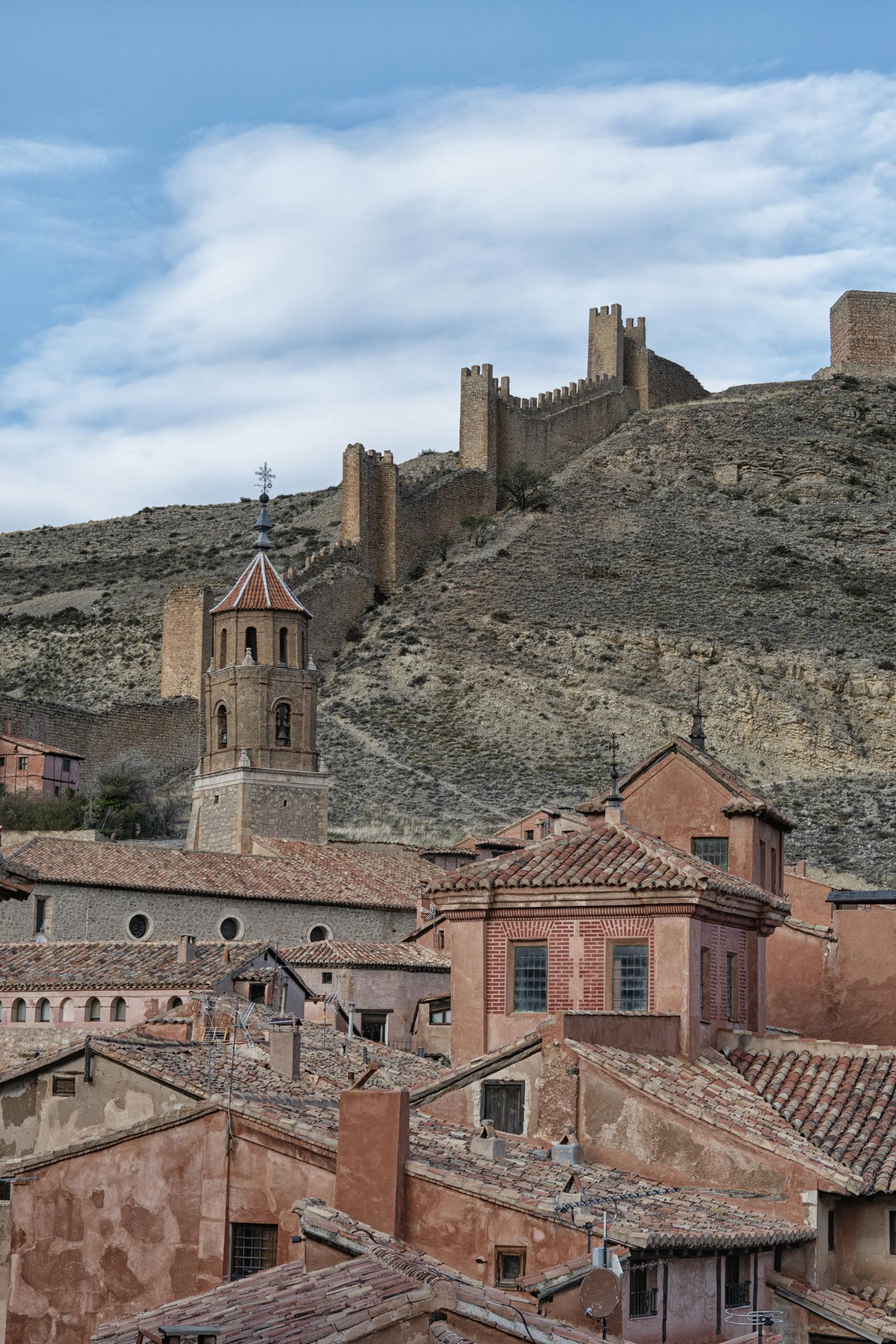 Charming Spanish village with historic buildings and castle walls on a hillside.